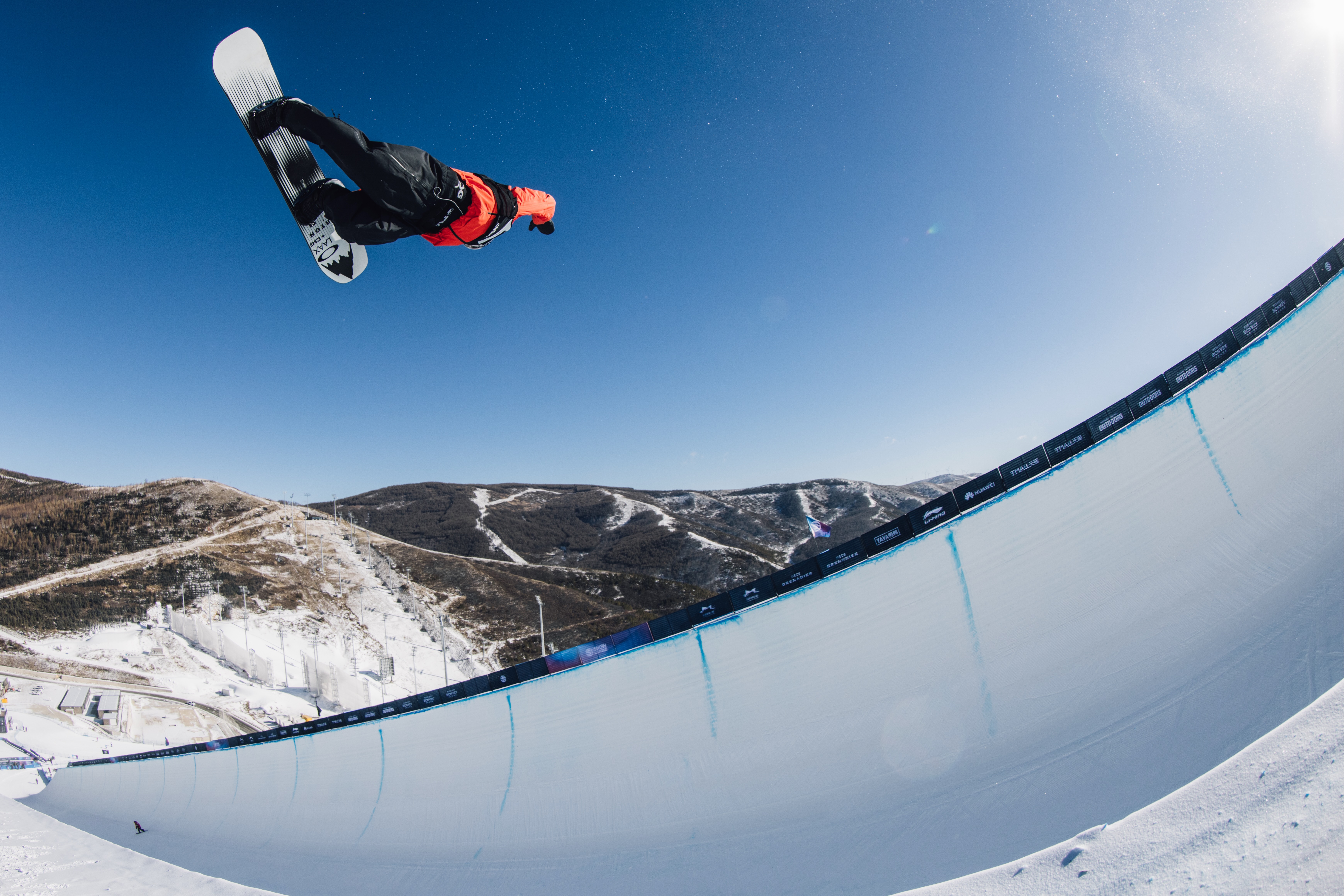 Jonas Hasler performing a freestyle snowboard trick above the halfpipe