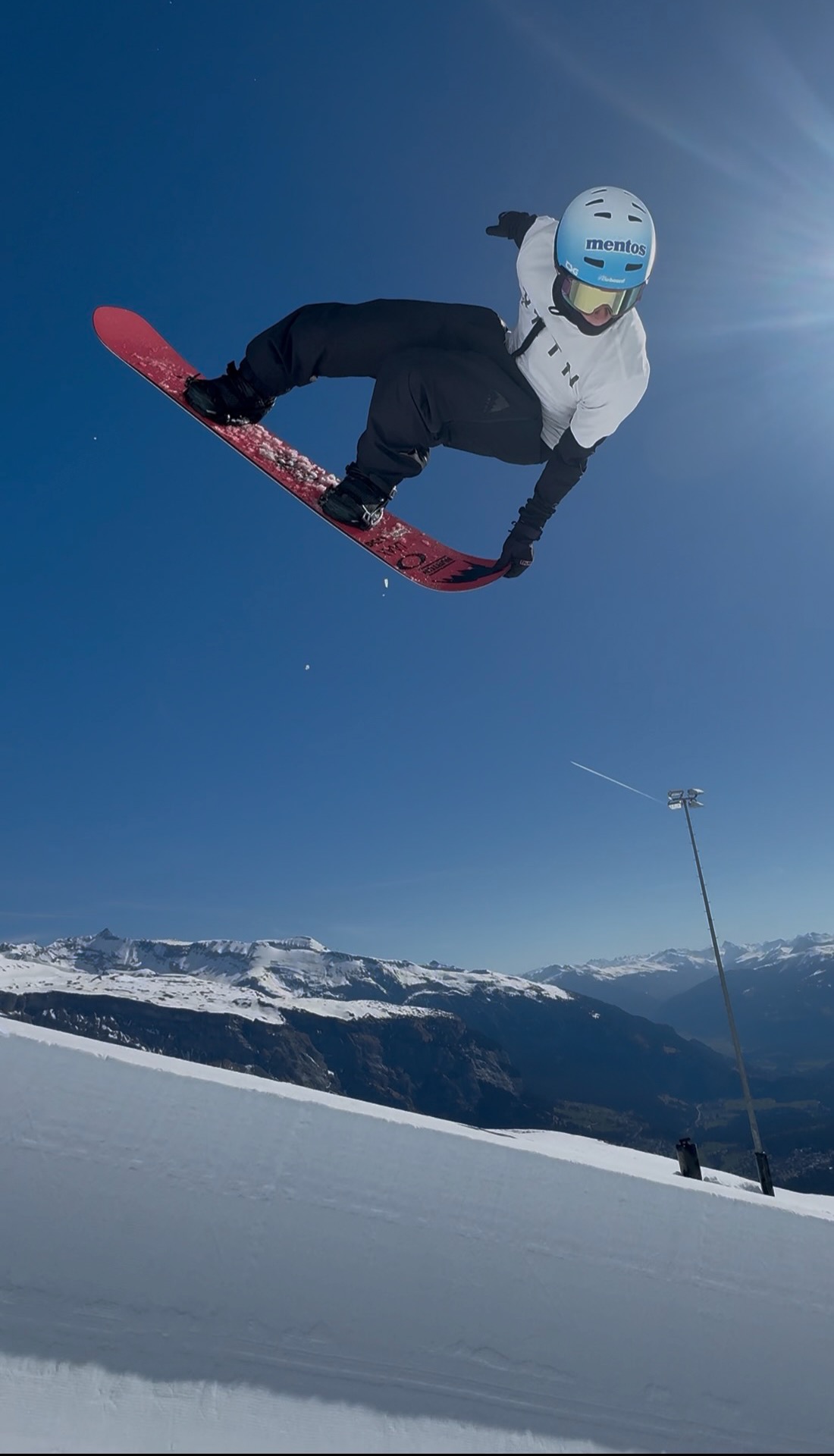 Jonas Hasler grabbing his snowboard high above a mountain halfpipe