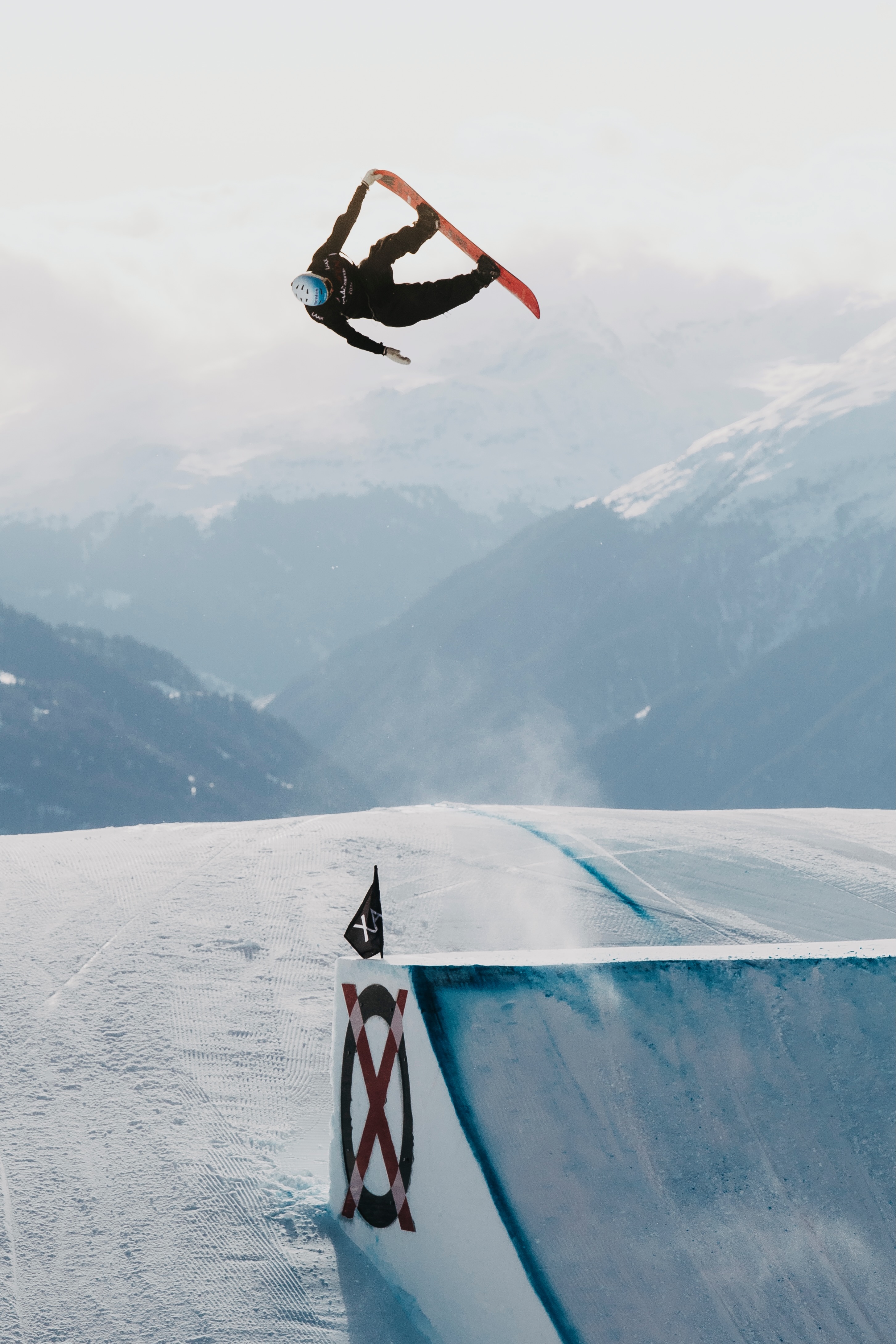 Jonas Hasler launching a snowboard trick above the clouds in Laax